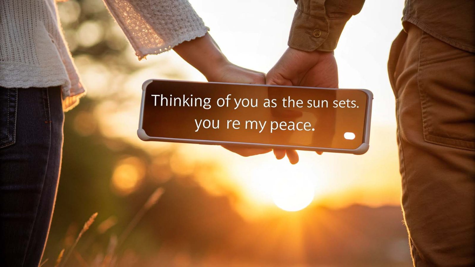Couple holding hands during sunset with smartphone displaying heartfelt good evening love message
